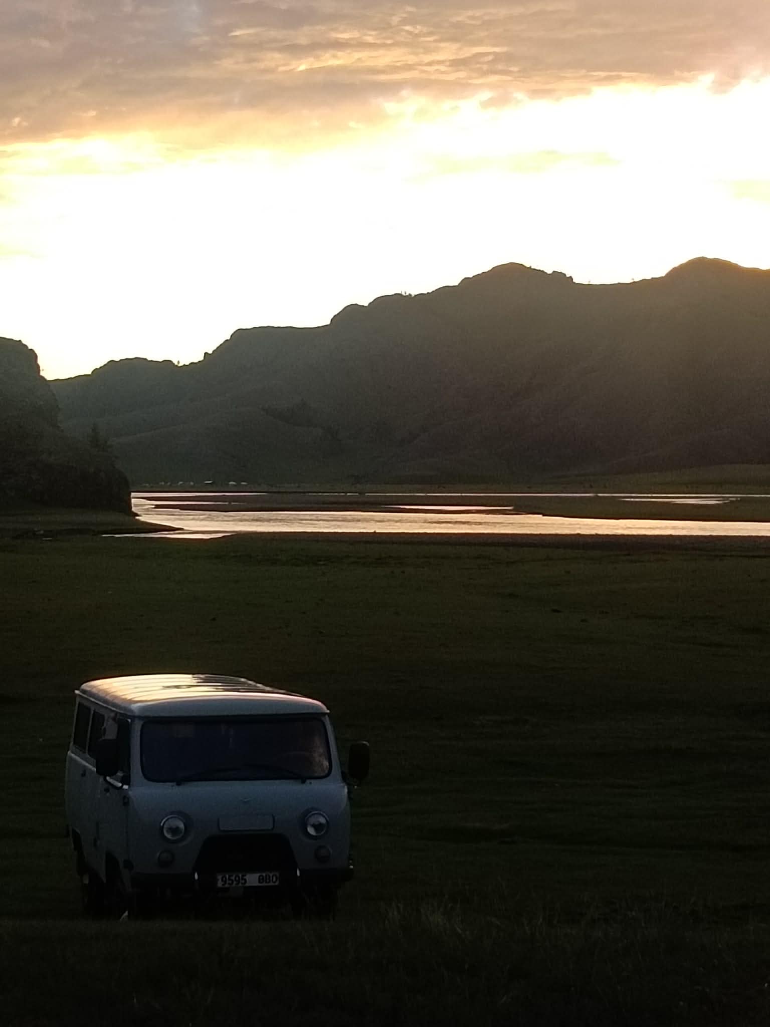 Van parked below a glowing river sunset