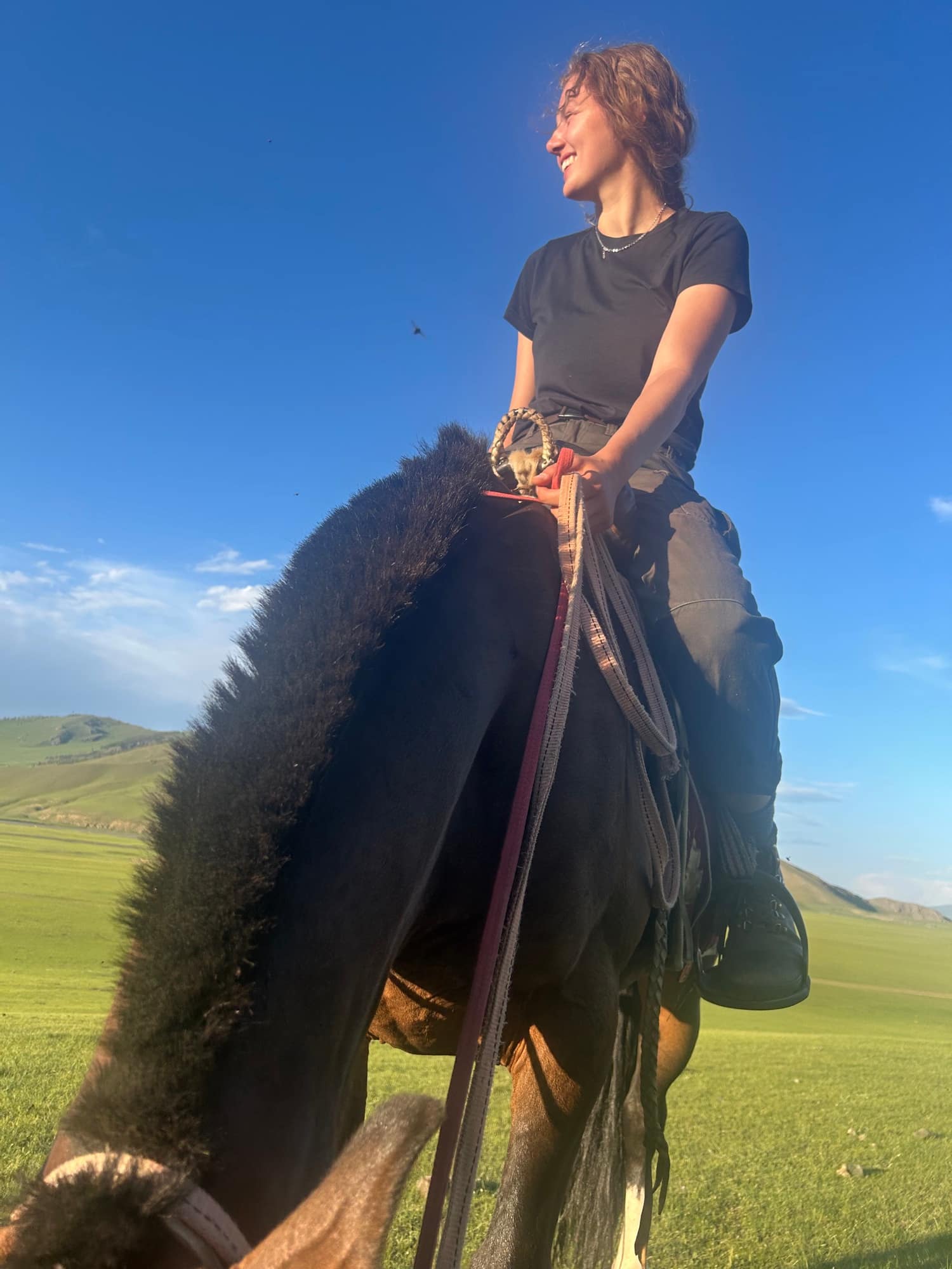 A guest laughing on horseback in the evening sun