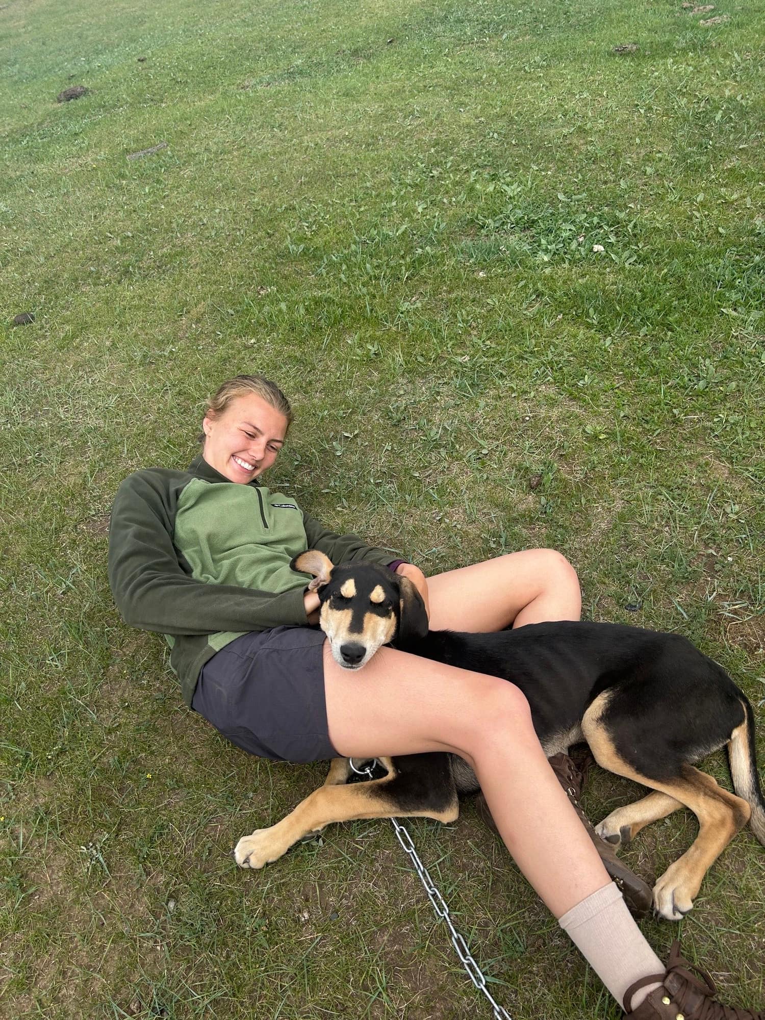 A guest lying on the grass with the camp dog