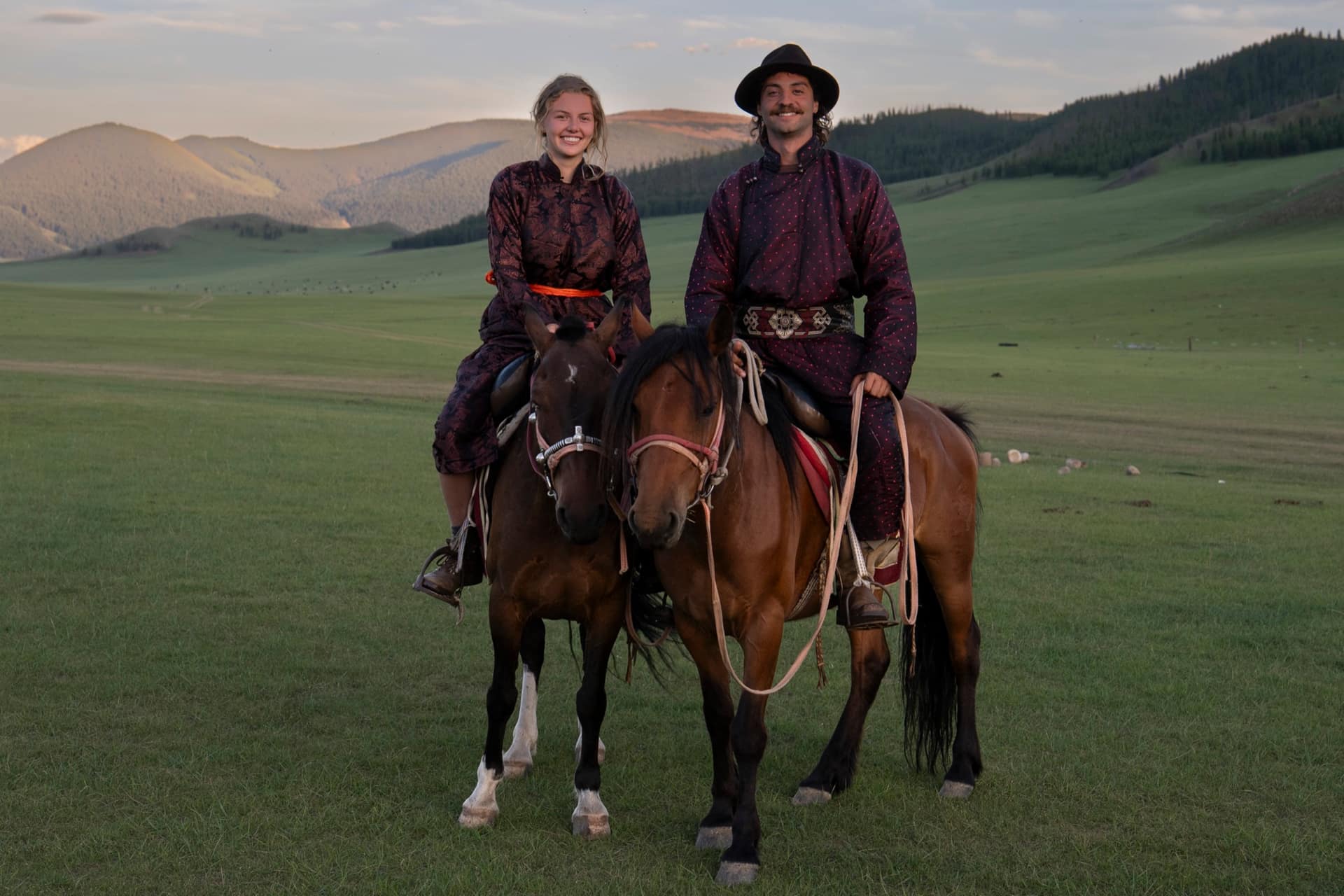 Two guests in borrowed deels on horseback in the evening light