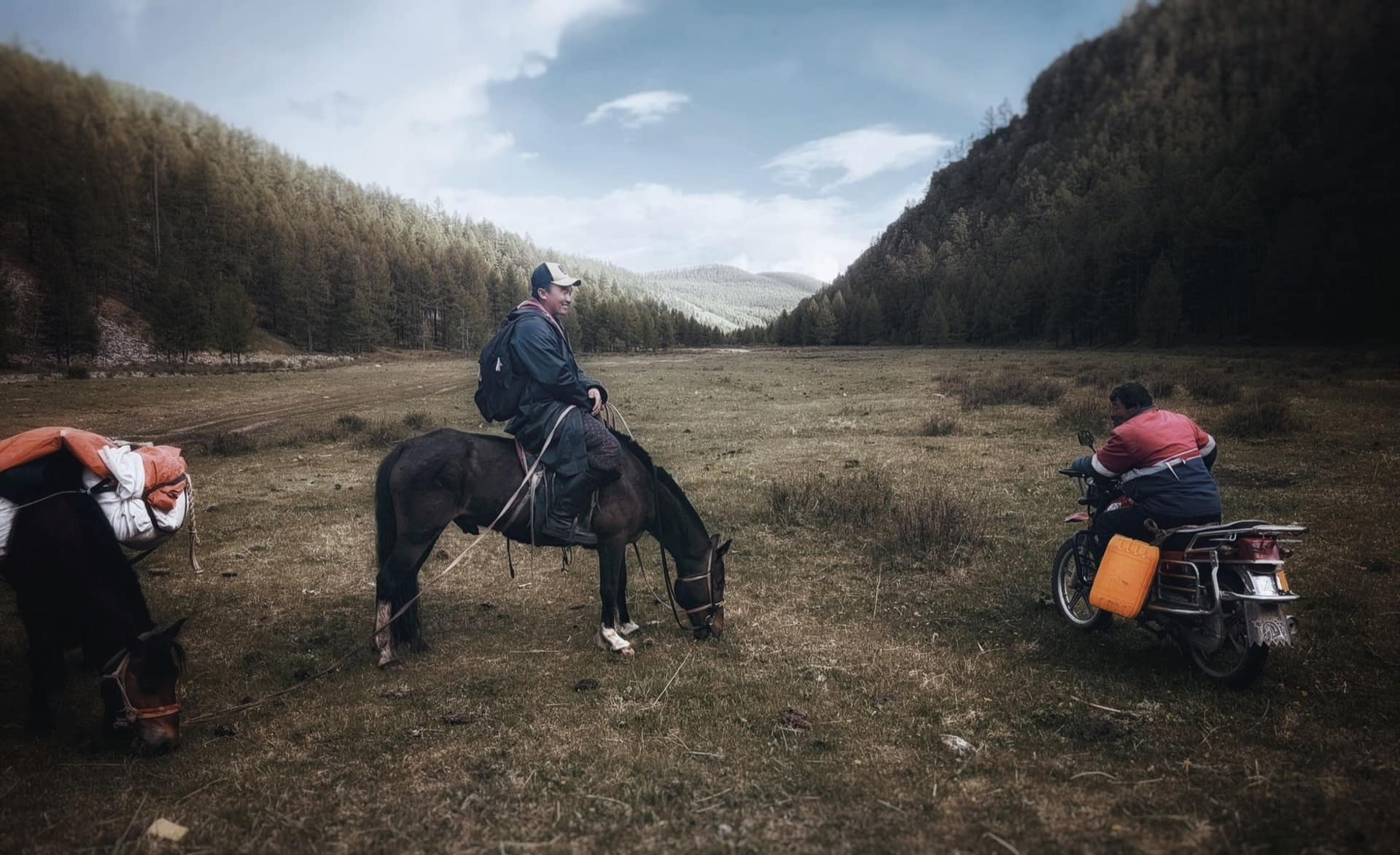 The guide on horseback meeting a herder on a motorbike in the valley