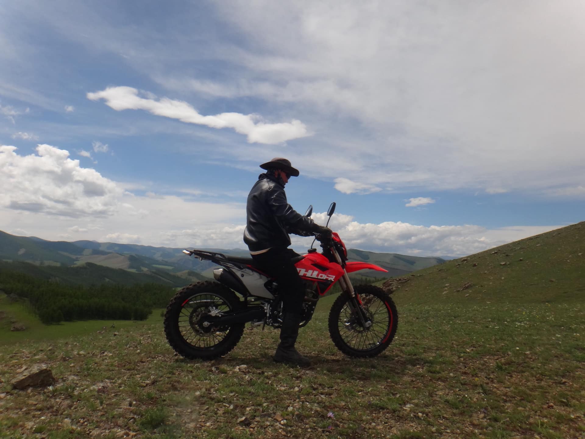 A herder pausing on his motorbike on the ridge