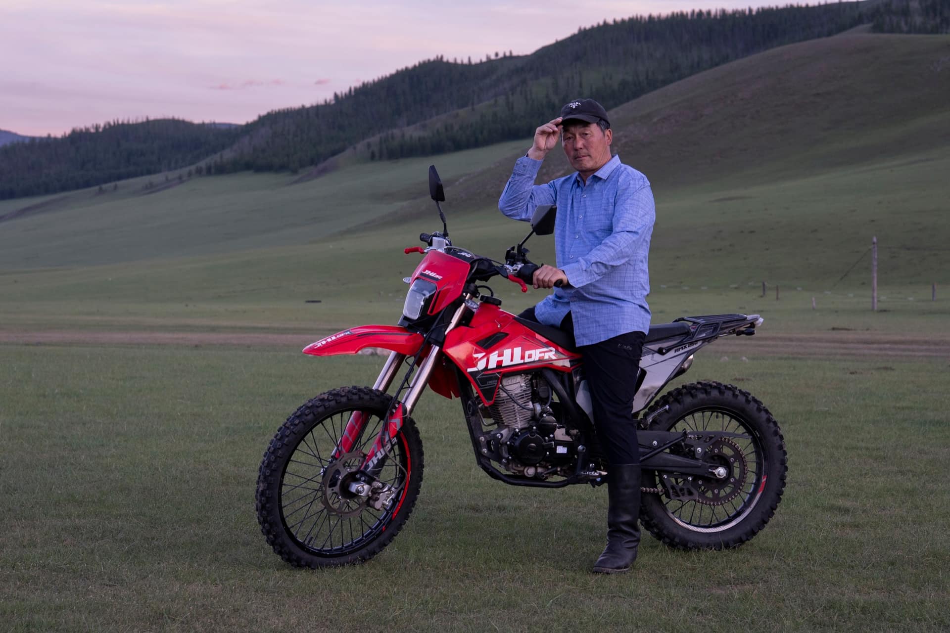 Herder resting on his motorbike on the steppe at dusk
