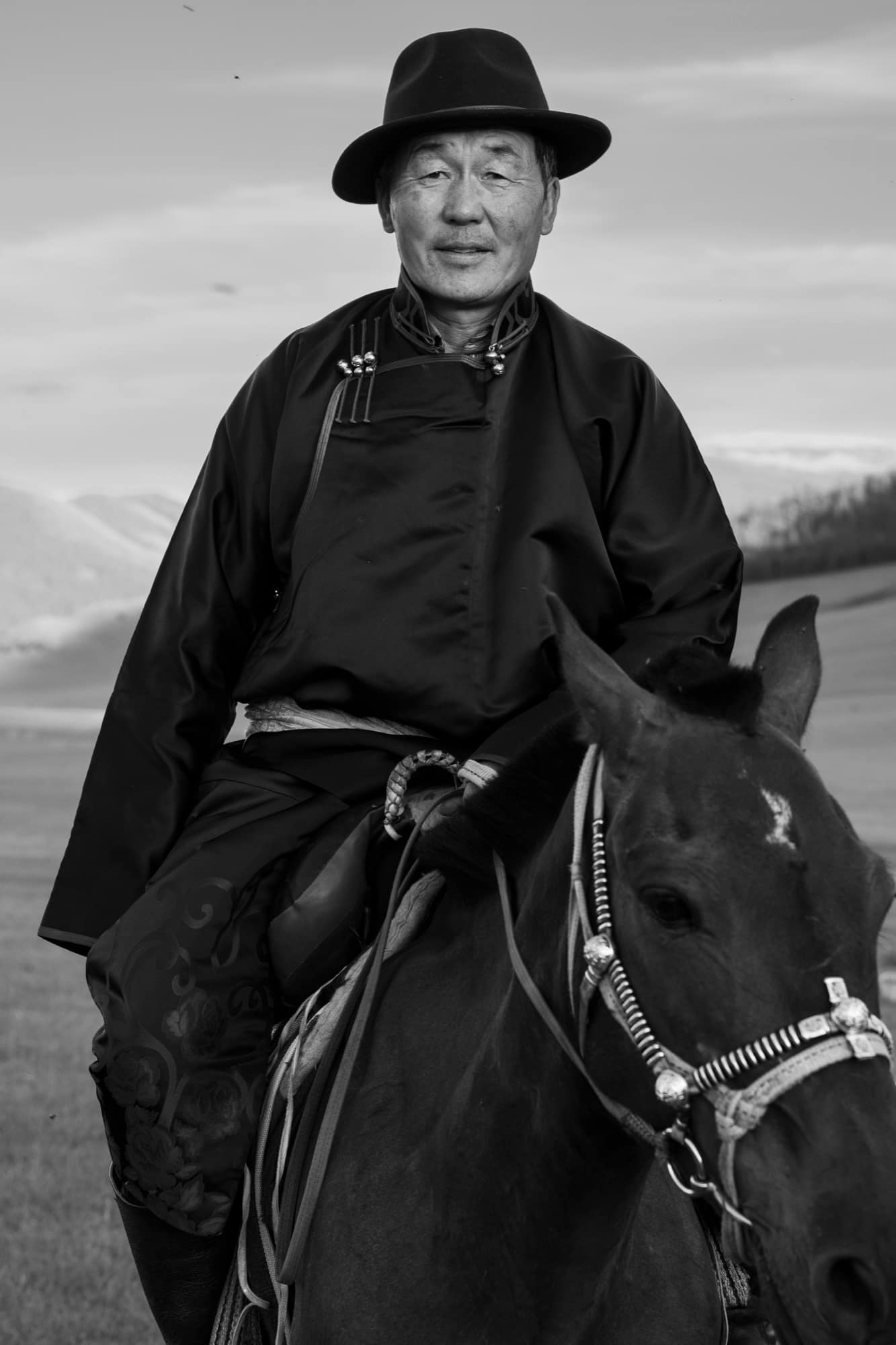 A horseman at ease in the saddle of his dark horse, in black and white