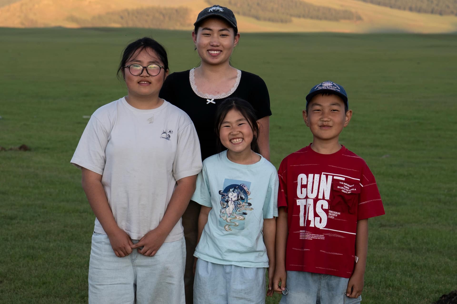 Four of the host family children together on the summer steppe at golden hour