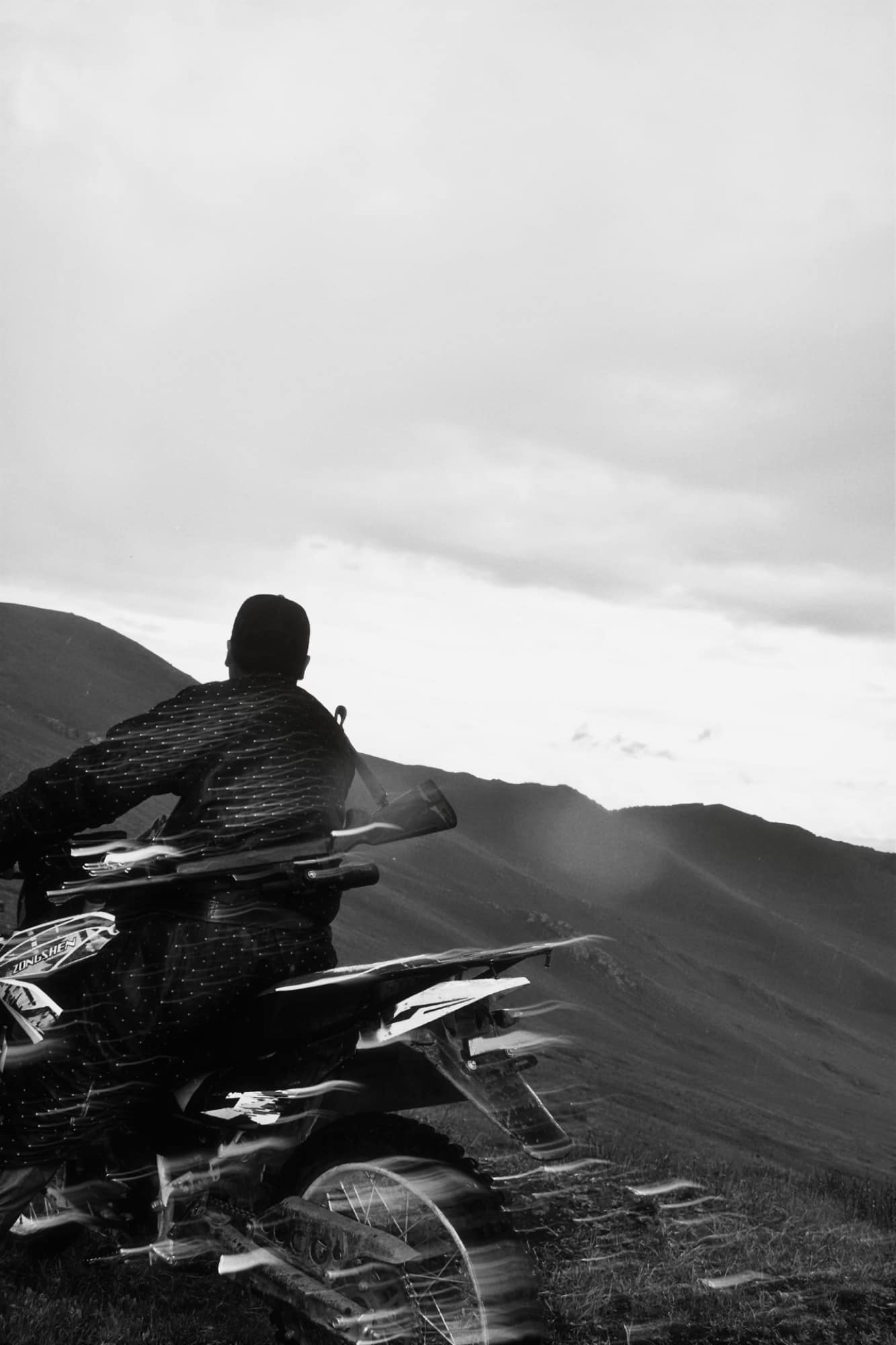 Rider pausing on a motorbike to look out across the ridgelines