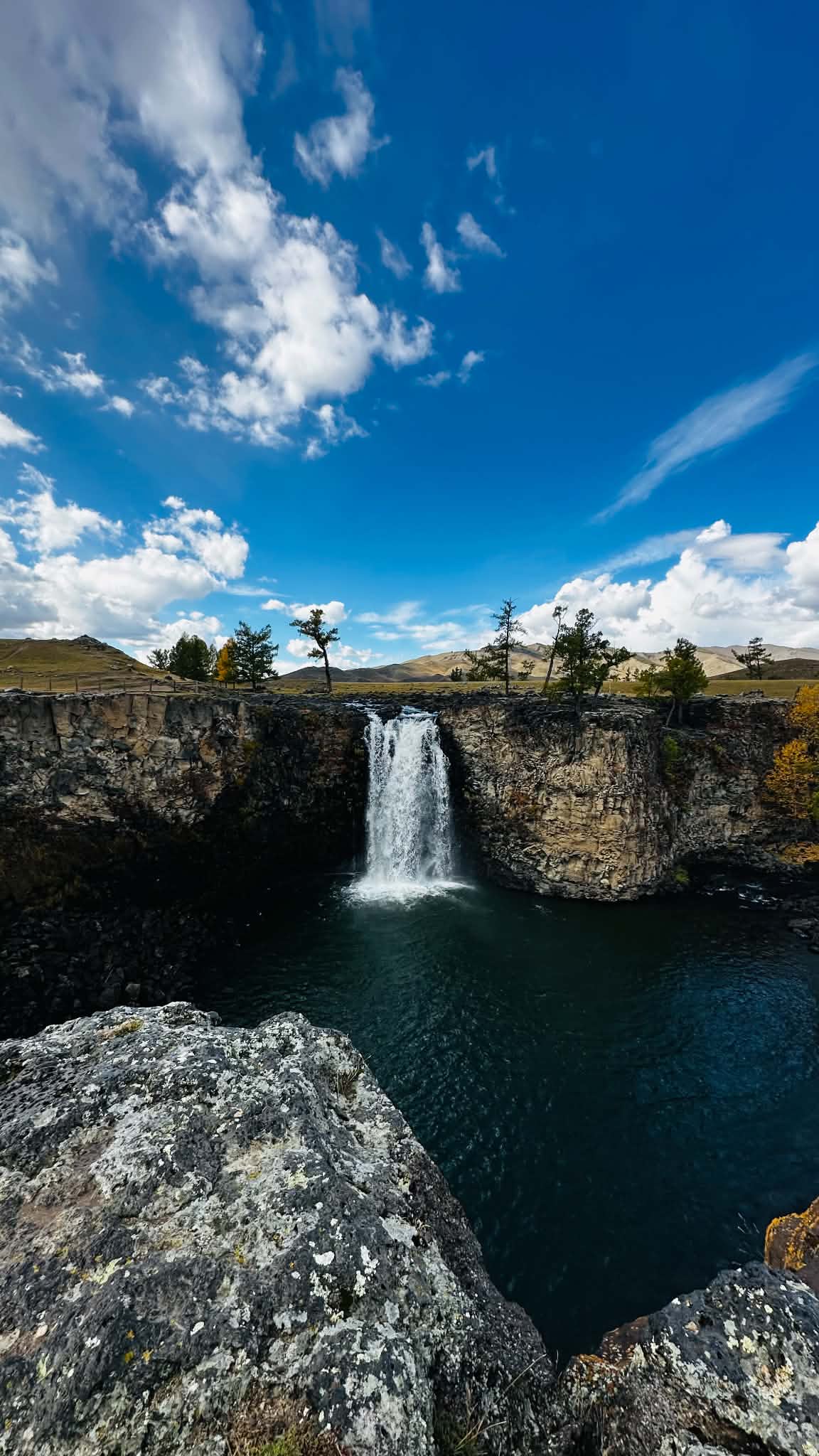 The Orkhon waterfall dropping into its pool, seen from the rock rim above