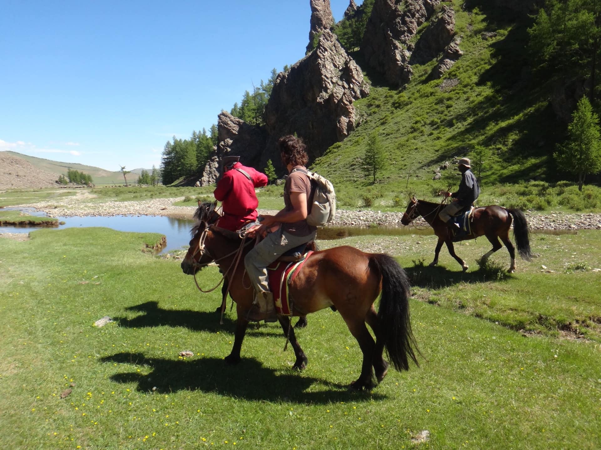 Riders crossing the river below rocky cliffs