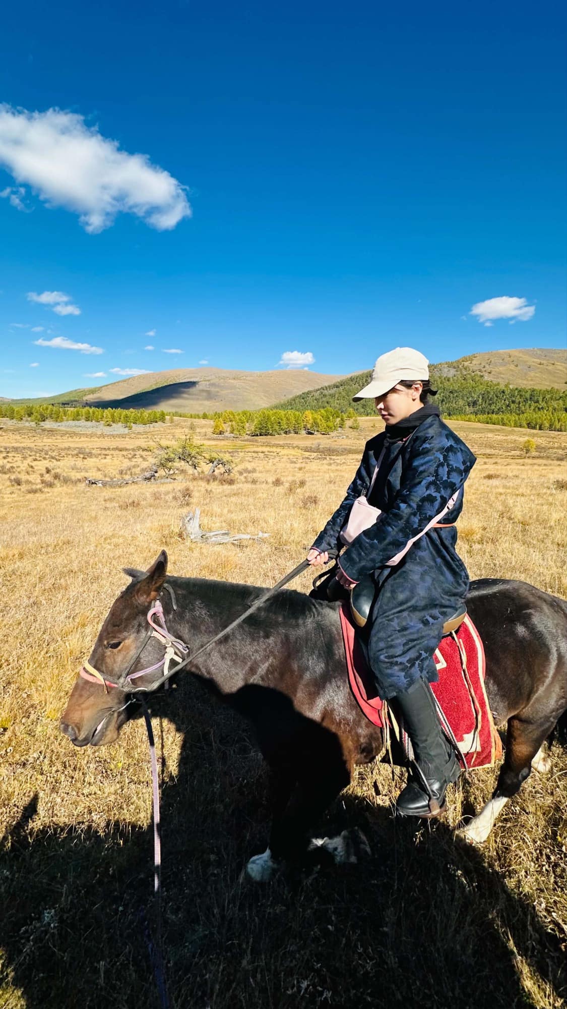 Riding across the golden autumn steppe below bare hills