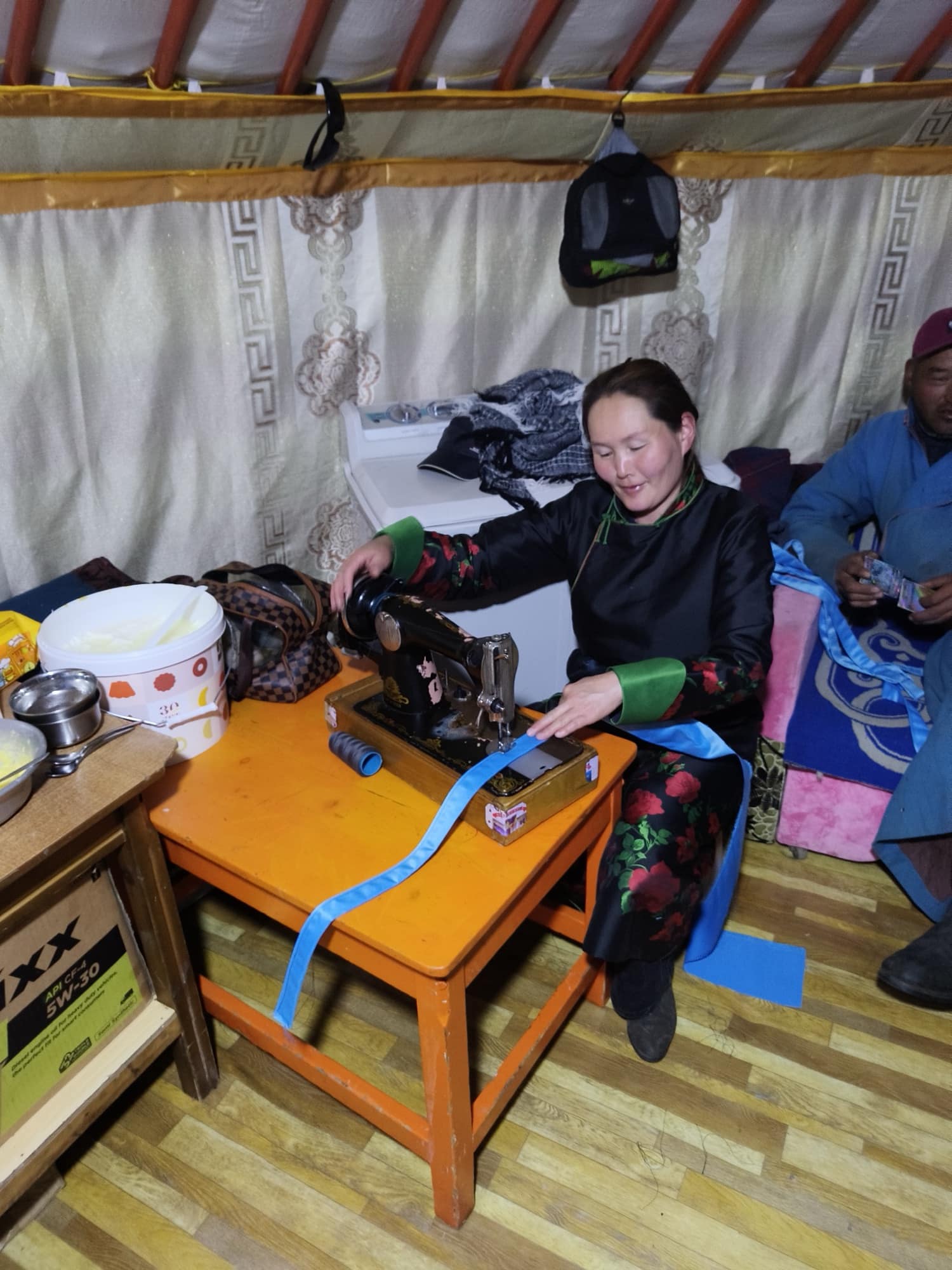 A host sewing on a treadle machine inside the ger