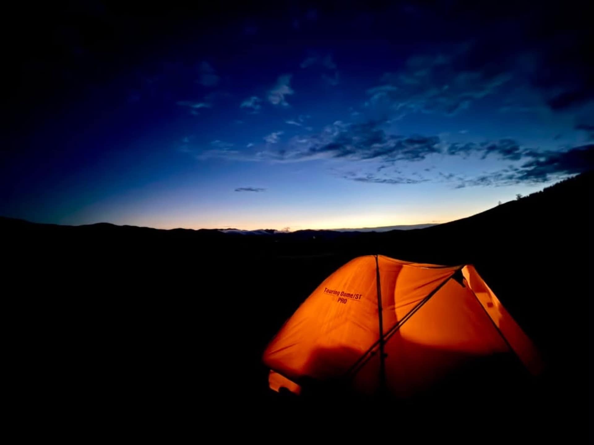 A lit tent on the steppe at blue hour